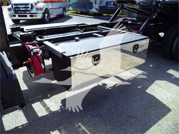Flatbed truck rear with a large silver toolbox mounted on the frame, red winch cable reel and mounting hardware visible.