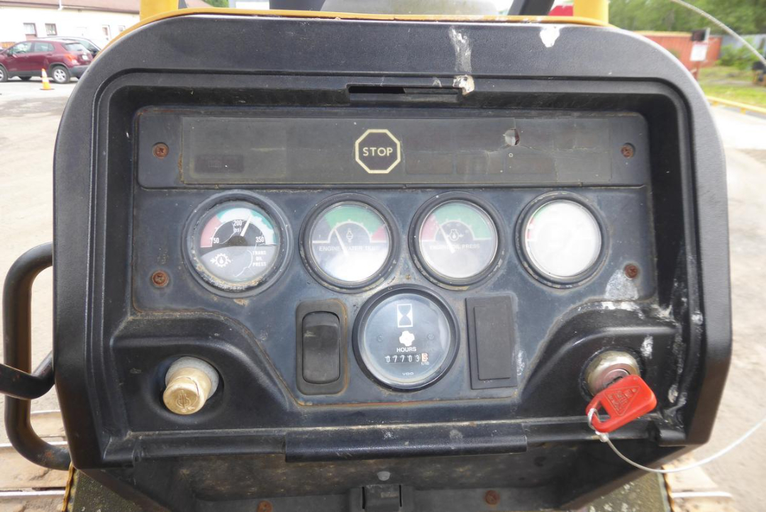 John Deere 650HLT cab dashboard with gauges, hours meter, ignition switch, and red key in slot.