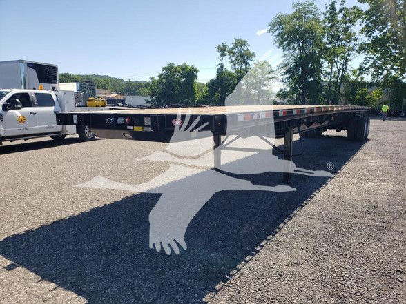 Flatbed trailer with long black frame and tandem axles; no clear branding visible on sides, VIN and stock number provided in listing context.