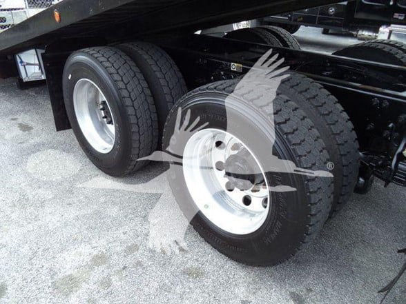 Peterbilt 348 wheel and dual rear axle tires under a lifted trailer with visible rims and tires.