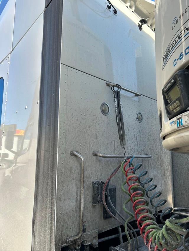 Rear exterior of a 2020 Peterbilt 579 sleeper cab truck showing polished metal side panel, air lines, and hitch area.