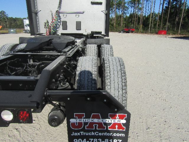 Kenworth T680 truck rear view showing dual rear axles, back of cab, and a mudflap with 'JAX TRUCK CENTER' logo and URL 'JaxTruckCenter.com' visible.