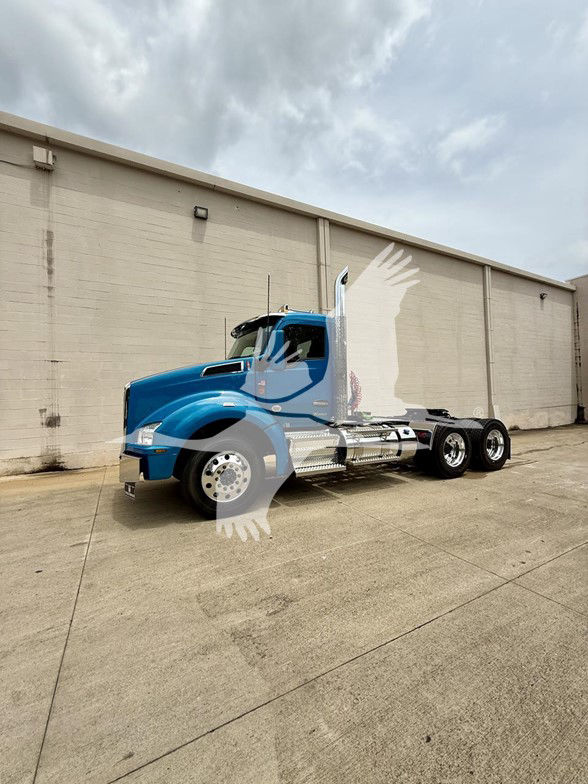 Blue 2026 Kenworth T880 daytime cab with dual rear axles, chrome fuel tanks, and high exhaust stack in an industrial yard.
