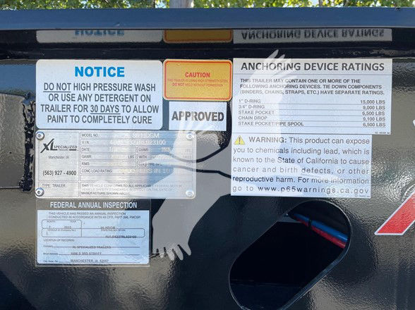 Trailer labels: notice about high pressure wash and paint cure; caution; approved; anchoring device ratings with weights; federal annual inspection sticker; VIN and trailer information plate; warning about exposure to chemicals including le