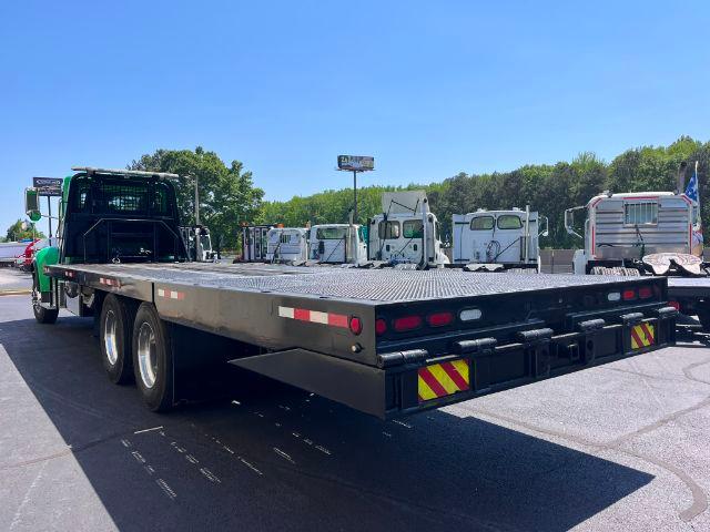 Peterbilt 348 rollback flatbed truck showing rear deck with reflective tape and dual rear axles.
