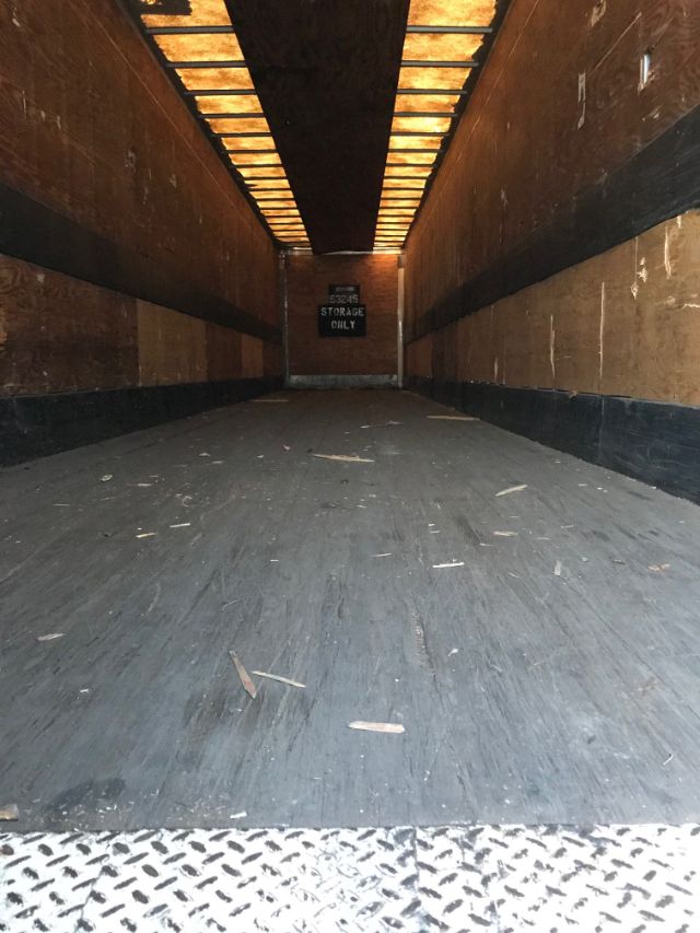 Interior of a rectangular dry van trailer with wooden walls and a painted metal floor; sign at far end reads 'Storage Only'