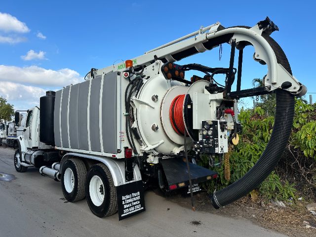 Rear view of a 2014 Freightliner M2 vacuum truck showing hose reel and waste tank with large suction hose.