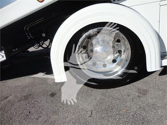Tow truck wheel and fender area showing polished hubcap and white wheel arch on a white International MV truck.