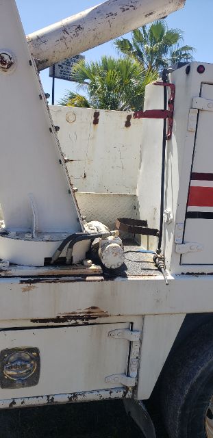Ford F550 mechanic truck bed showing hydraulic lift and hydraulic lines with white painted metal surface and reflective stripes.