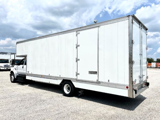 Ford F650 moving van box truck side/rear view with white cargo box and cab, shown in an open lot.
