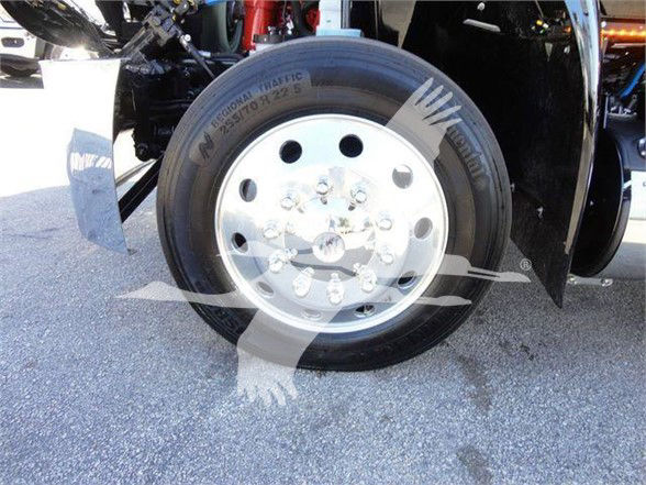 Truck tire and wheel assembly showing a dual rear wheel setup with a polished aluminum rim and lug nuts; faint text on tire sidewall.