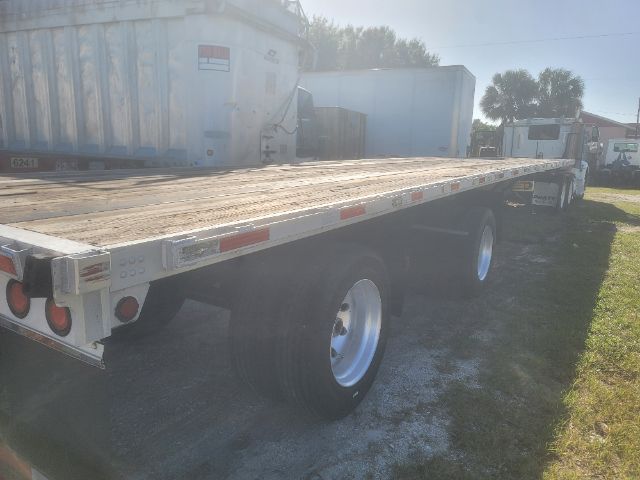 Flatbed trailer with a long wooden deck and dual rear tires, 2003 Utility 48x102, in-service condition.