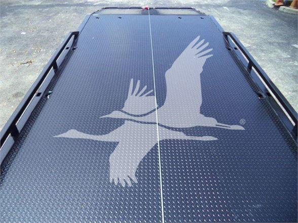 Flatbed truck bed with diamond plate pattern and a large white bird graphic decal. Guard rails along edges with a center seam line.