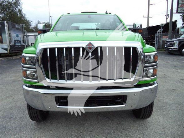 Front view of a bright green 2023 International CV truck with large chrome grille and bumper. Watermark overlay of a logo on center grill.