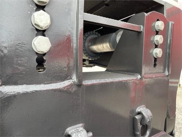 Trailer hinge area showing hydraulic or mechanical linkage with bolts and a roller shaft visible.