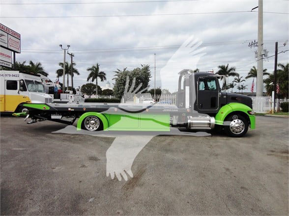 2022 Peterbilt 337 tow truck side view showing green and black cab with white exhaust stacks and flatbed tow chassis.