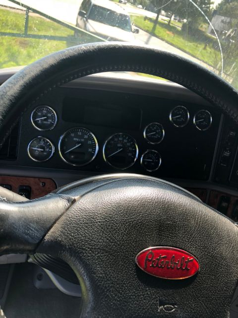 Peterbilt steering wheel and gauge cluster inside cab showing multiple round gauges.