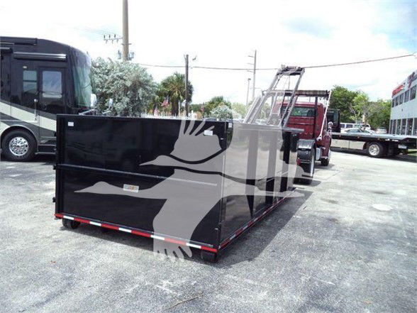Freightliner business class M2 106 truck with a large black utility/waste management body attached, parked in lot with other trucks visible.