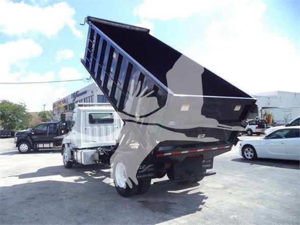 Dump truck bed raised showing the open-top dump mechanism; visible text: none clearly legible on surfaces.