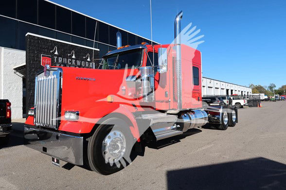 Kenworth W900L conventional sleeper truck in red with chrome exhaust stacks and large front grille, parked in lot.