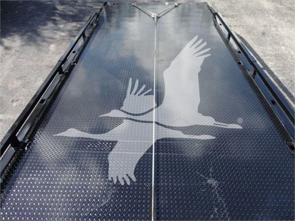 Truck bed with diamond plate surface and transfer logo featuring two birds in flight.