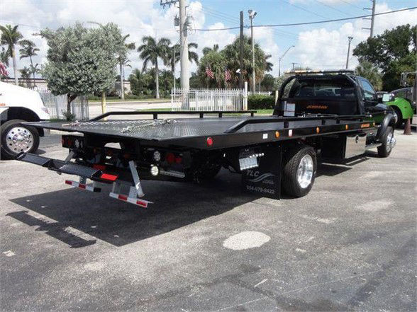 Ram 5500 tow truck flatbed showing rear and side view with reflective lights and wheel, bumper, and hydraulic system components.