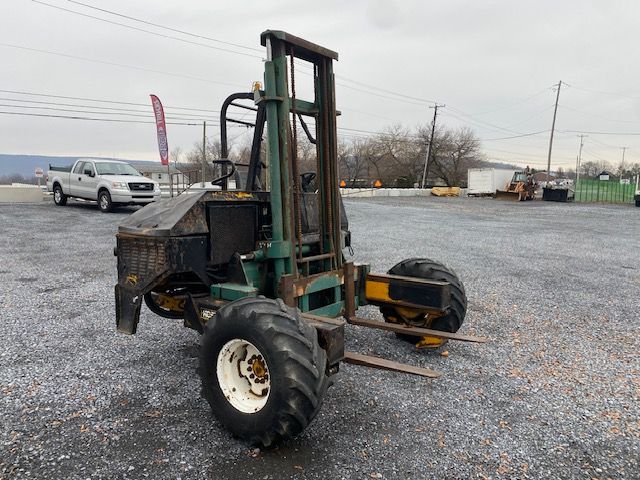 Kesmac F5000 forklift/thin-tire truck with green frame, black engine housing, and large off-road tires in a gravel lot.