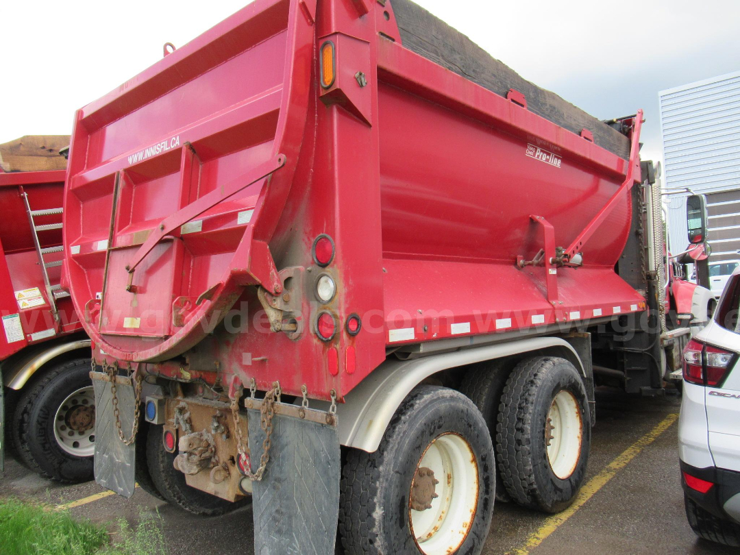 Red dump truck/5-axle Mack GU713 dump showing rear dump bed, taillights, chains, and mud flaps.
