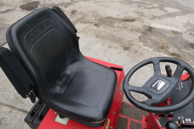 Tractor seat and steering wheel from a Steiner 415 tractor with black seat and circular steering wheel.