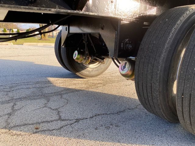 Trailer undercarriage showing dual rear axles with air suspension bags and tires; no legible model numbers visible.