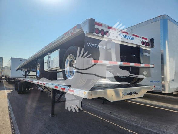 Flatbed trailer showing Wabash branding and dual rear lights on the back, on a loading dock trailer bed.