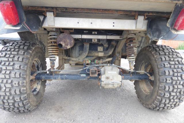 Rear view of a 2017 Club Car Carryall 1700 showing solid axle, suspension coils, differential, and off-road tires.