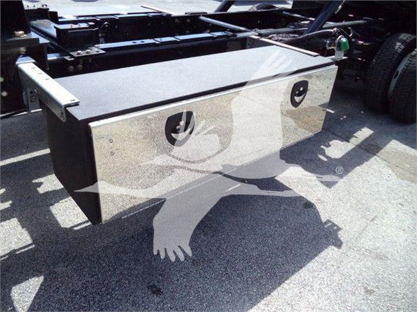Flatbed or toolbox-style large metal storage box mounted near rear of truck chassis with two circular access openings and black handles.