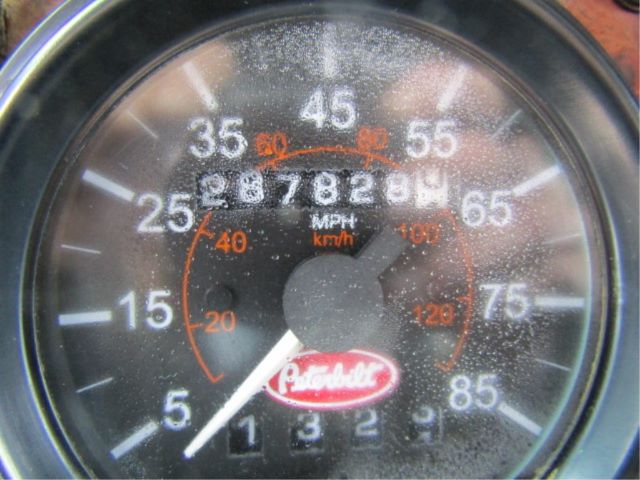 Dial gauge showing speedometer with numbers 5 to 85 mph, inner orange km/h ring, central odometer digits, Peterbilt logo at bottom.