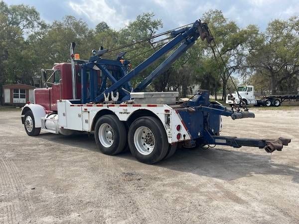 Peterbilt 359 tow truck with red cab and white service body, blue boom hoist, and rear equipment rack