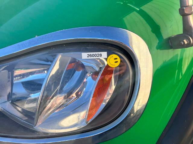 Headlight area of a green 2016 Freightliner M2 106 truck with chrome bezel and yellow inspection sticker