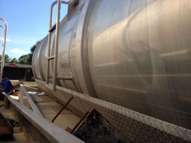 Tanker vacuum tank trailer on a flatbed with diamond plate step and ladder rail.