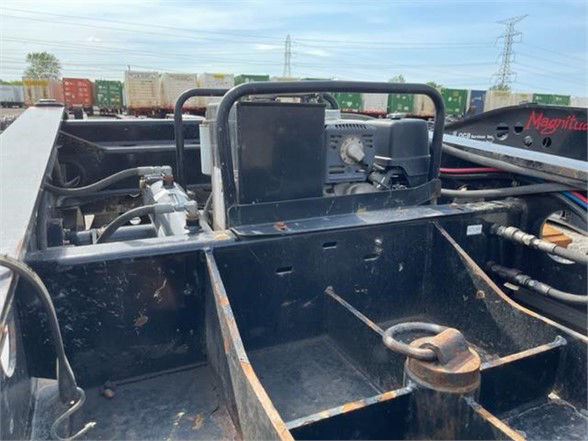 Lowboy trailer engine bay area showing pony motor and hydraulic components with hoses and fittings.