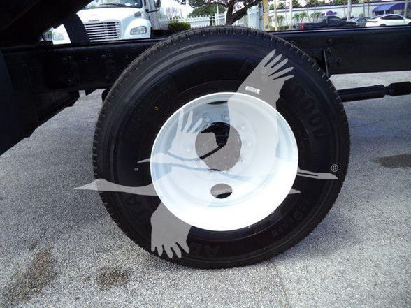 Truck wheel with black tire and white steel rim in a landscape truck bed