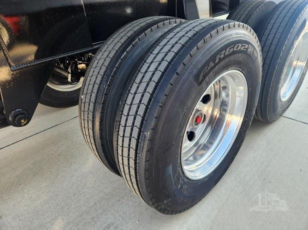 Trailer dual rear axles with large Goodyear tires and polished rims, part of a steel end dump trailer chassis.