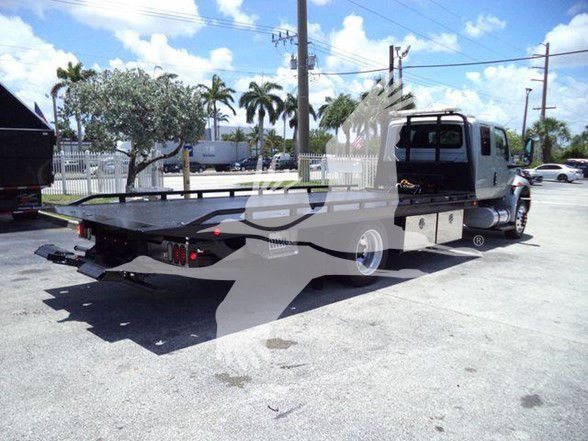 Tow truck with flatbed in side view showing rear deck and dual rear lights.