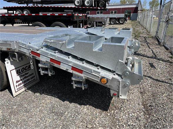 Manac steel steeldeck trailer rear corner showing silver galvanized metal with triangular rack sections and wiring/lighting near the bumper.