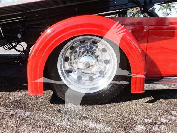 Red Peterbilt 337 fender showing polished chrome wheel with circular holes and tire.