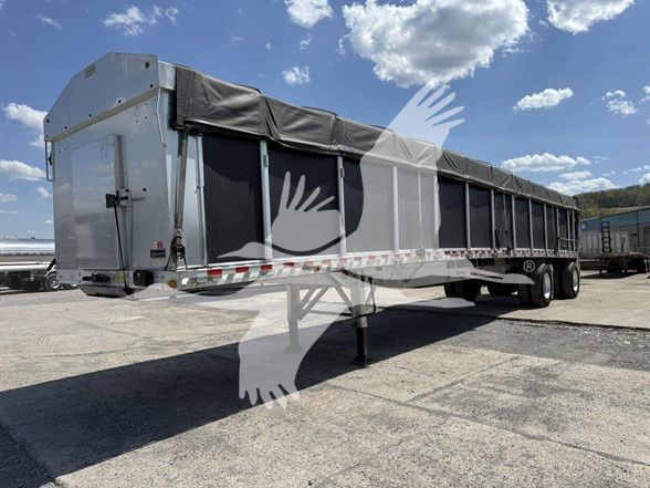 2022 Reitnouer Big Bubba flatbed trailer with black tarpaulin cover, side rails, and tandem axles; front hitch and support leg visible.