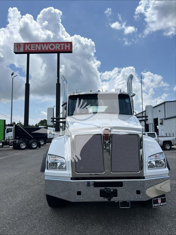 Kenworth T880 front view in white, with large chrome grille, two tall exhaust stacks, and Kenworth signage visible in background.
