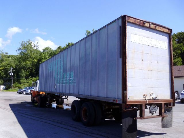 Fruehauf F69-F2-45 trailer in a lot, side and rear views visible, blue weathered container, rusted frame and dual rear wheels.