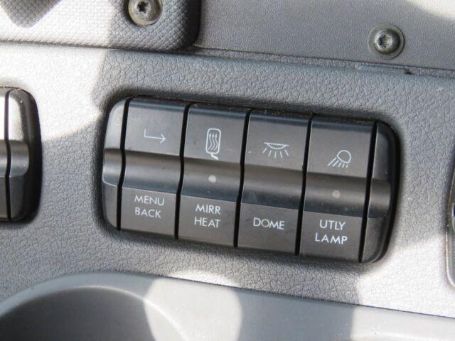 Dashboard control panel of a Freightliner Cascadia Evolution showing six labeled buttons: from left to right on top row icons for turn signal/arrow, heated window, interior light, and exterior light; bottom row labeled from left: MENU BACK,