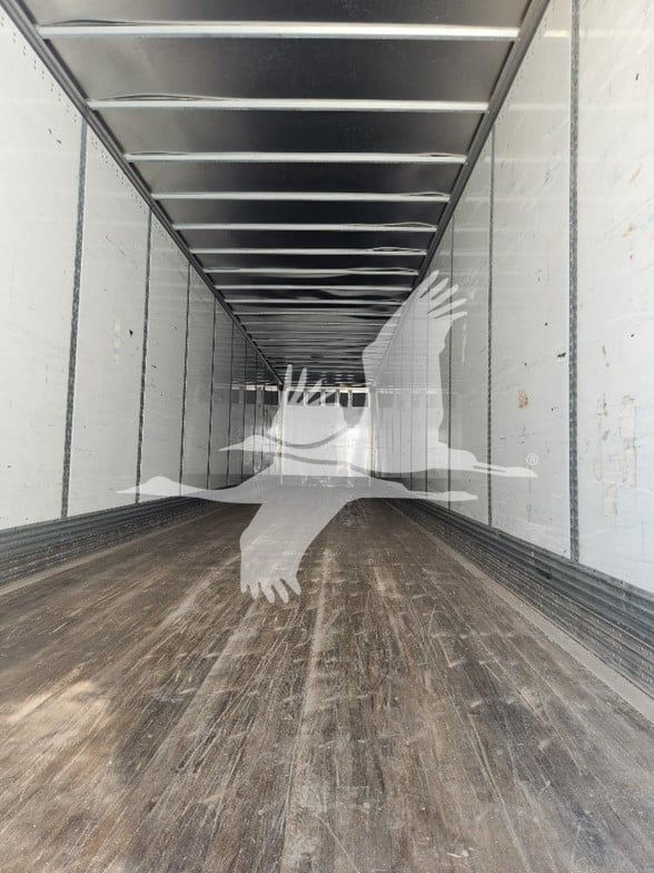 Interior of a Wabash trailer cargo area showing long empty aluminum sidewalls and wooden floor with overhead rail tracks.