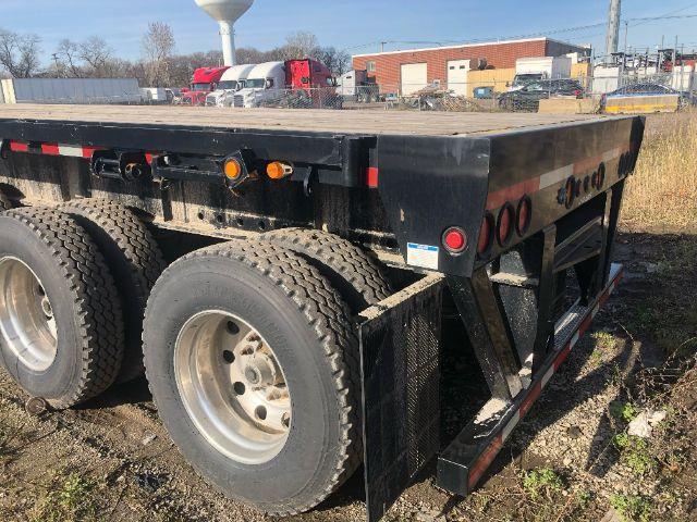 Load King PF 948 oilfield flat deck trailer showing dual rear wheels, black steel deck, and rear safety steps with lights and reflectors.