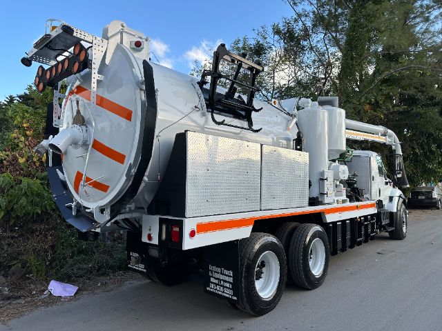 Vacuum truck showing a large cylindrical rear tank with orange reflectors, rear access ladder, and multiple compartments on a white truck chassis.